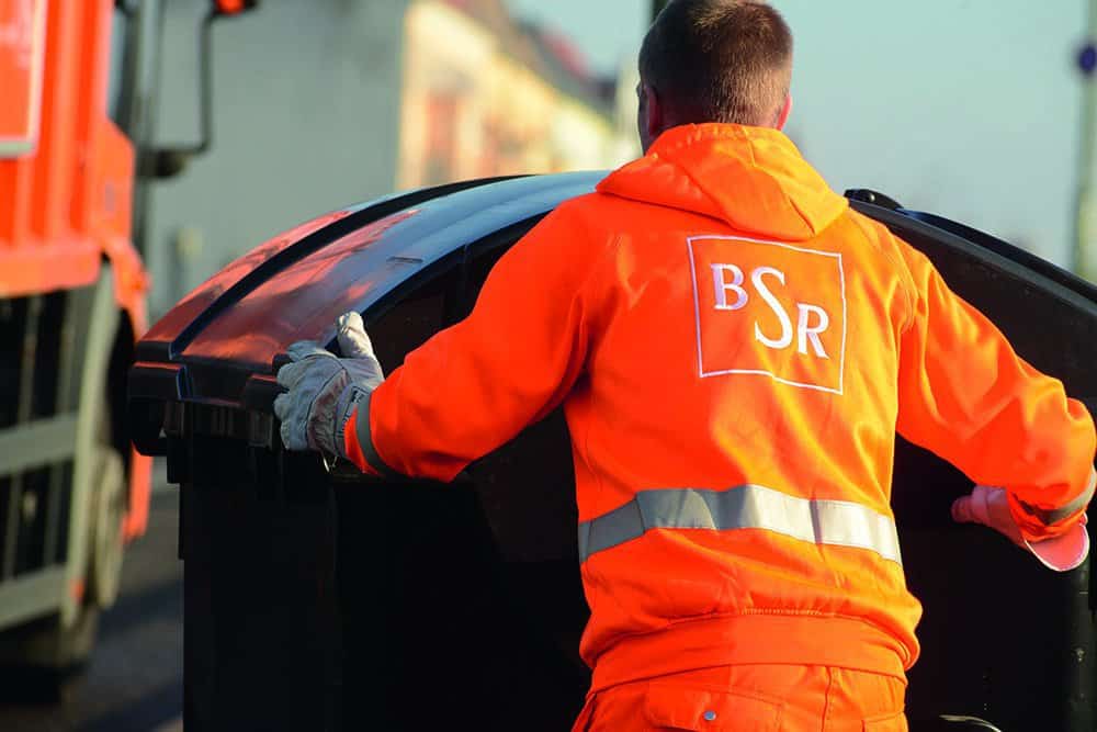 Ein Mitarbeiter der BSR bringt einen Müllcontainer zum Fahrzeug