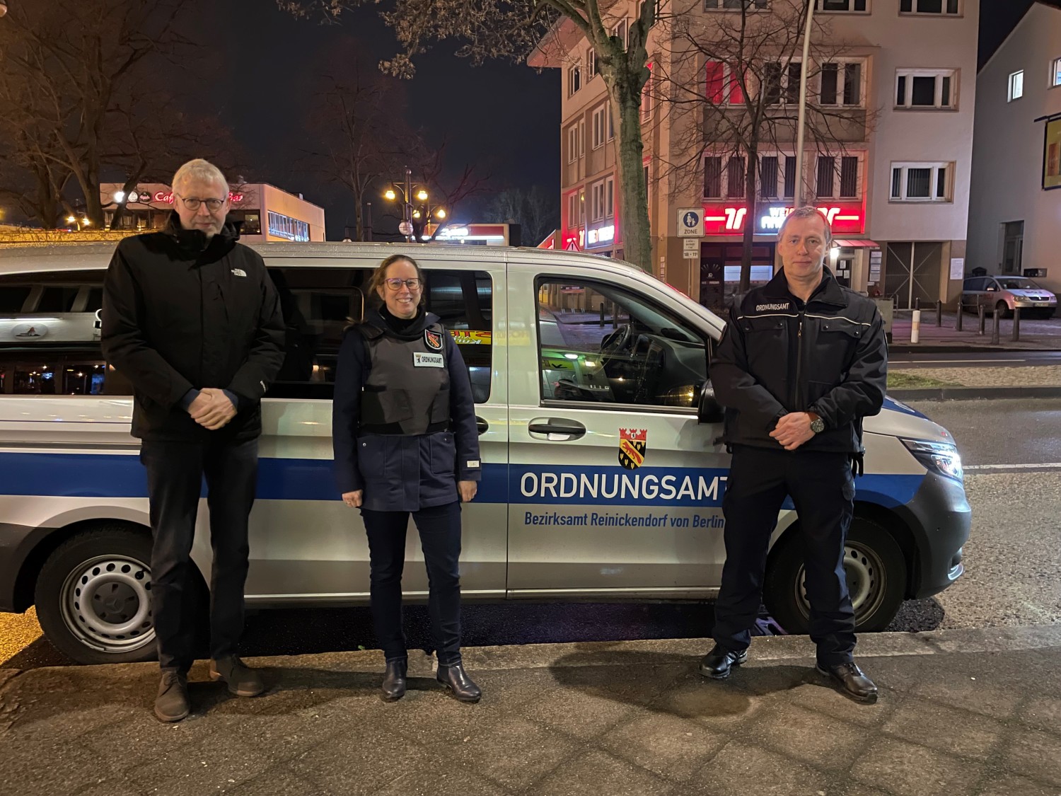 Drei Menschen vor Ordnungsamt-Auto