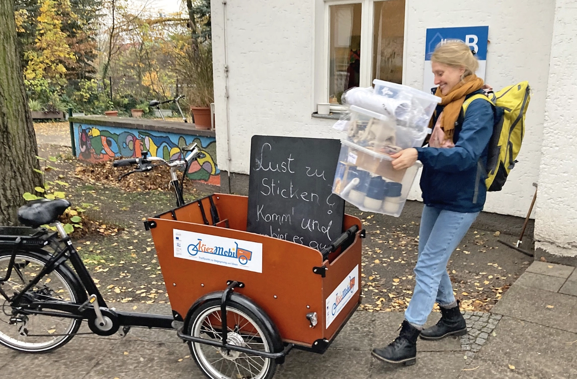 Eine Frau belädt einen Fahrradanhänger.