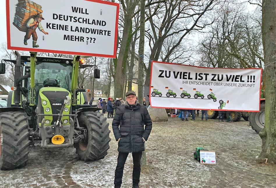 Ein Mann vor einem Traktor und mehreren Demonstrationsspruchbändern