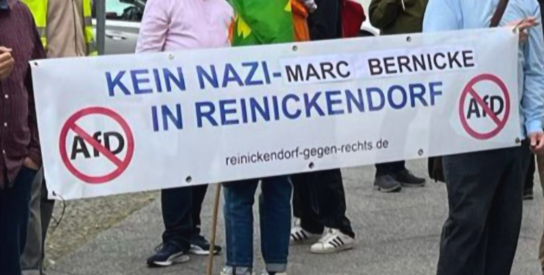 Menschen halten ein Banner hoch, auf dem steht "Kein Nazi in Reinickendorf / Marc Bernicke", daneben durchgestrichene AfD-Schriftzüge.