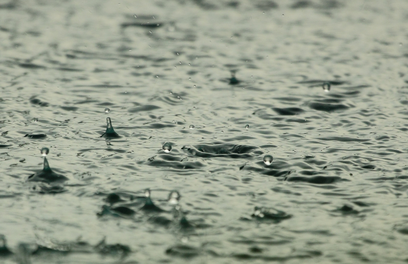 auf dem Boden stehendes Wasser, in dass viele Regentropfen prasseln.