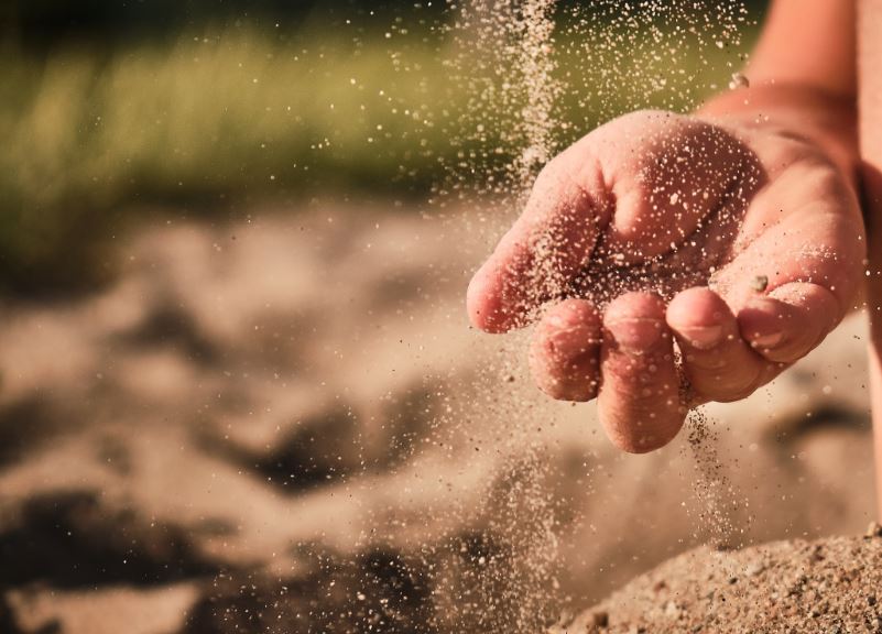 Sand rieselt auf eine Kinderhand