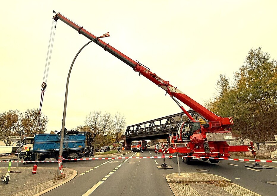 Ein Kranausleger, der quer über eine Straße reicht, stabilisiert einen Laster.