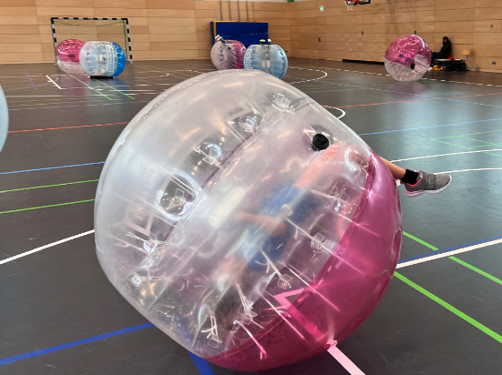 Eine Sporthalle, im Vordergrund ein rosafarbener Bubble-Soccer-Ball