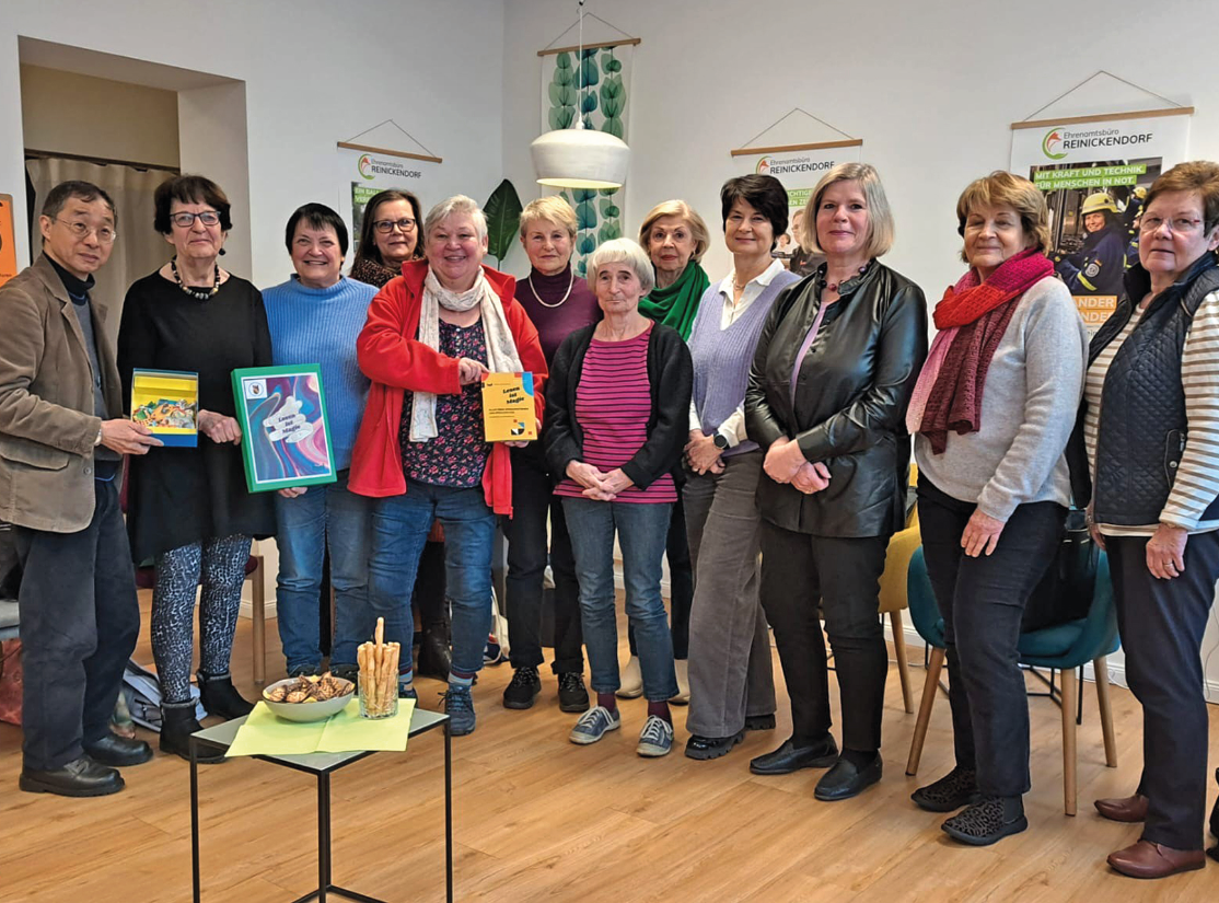 Eine Gruppe von zwölf Frauen steht aufgereiht quer vor der Kamera. Sie wirken fröhlich, haben Bücher in der Hand.