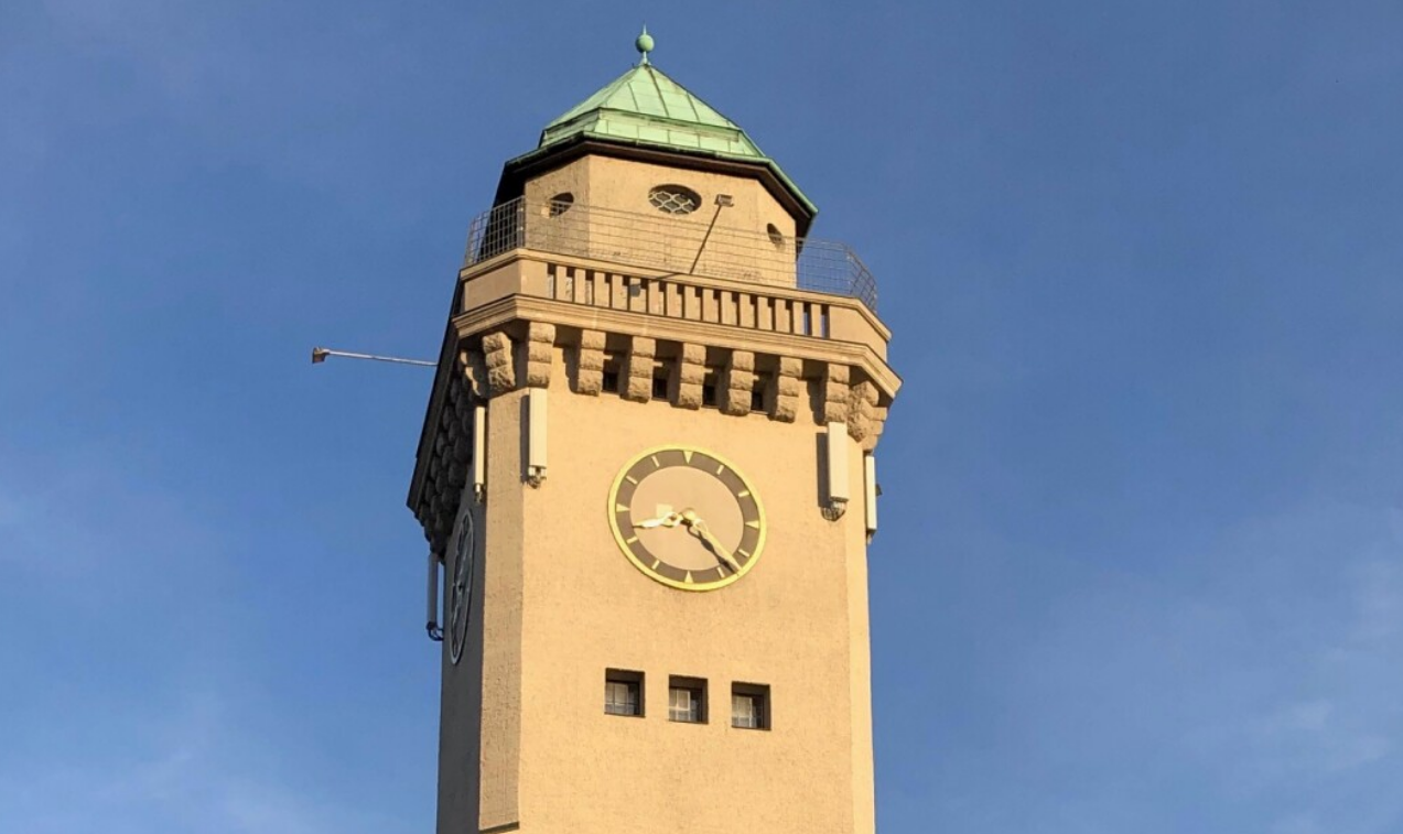 Die Spitze eines Turms mit Turmuhr vor blauem Himmel