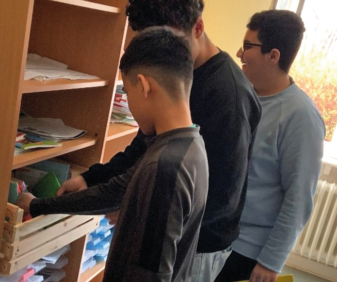 Schüler stehen an einem Bücherregal und nehmen Bücher heraus