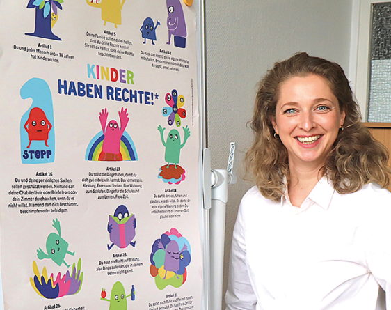 Eine Frau steht vor einem Plakat mit der Aufschrift: Kinder haben Rechte