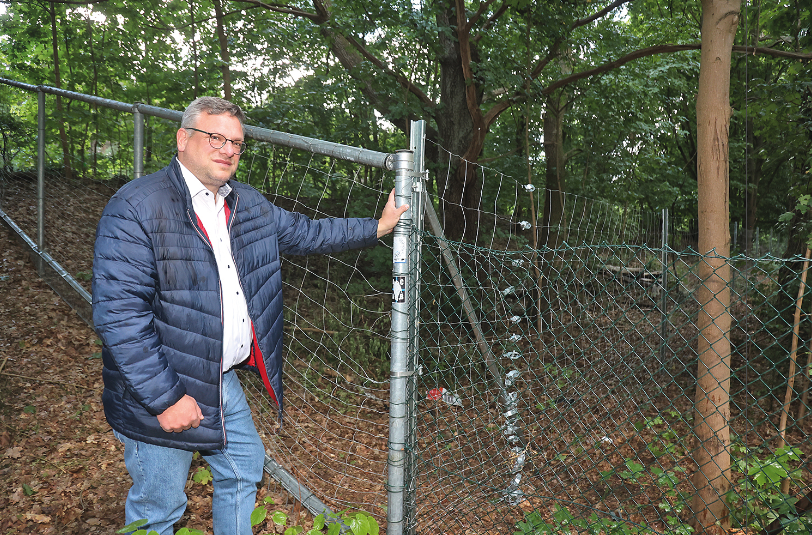 Ein Mann steht an einem Zaun im Wald