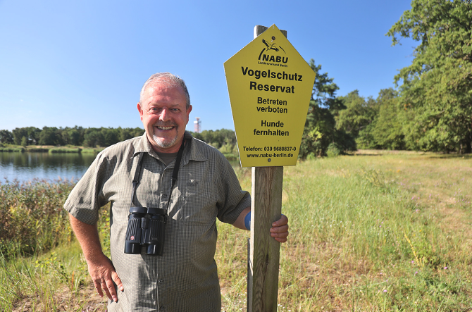 Ein Mann an einem Schild bei einem See