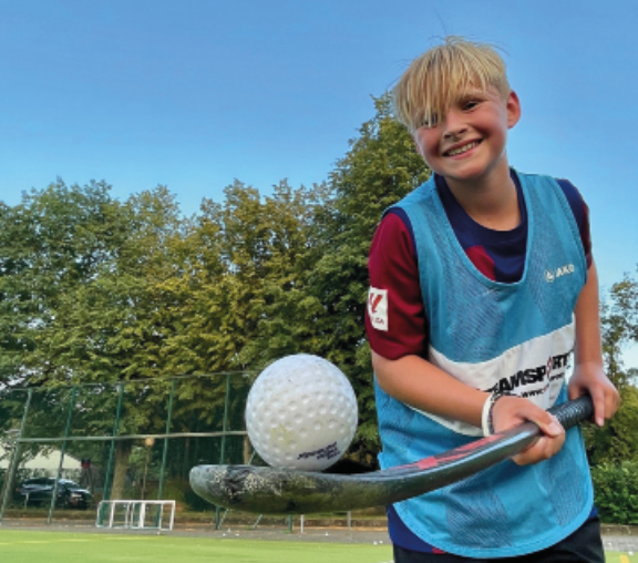 Ein lachender Junge mit einem Hockeyschläger