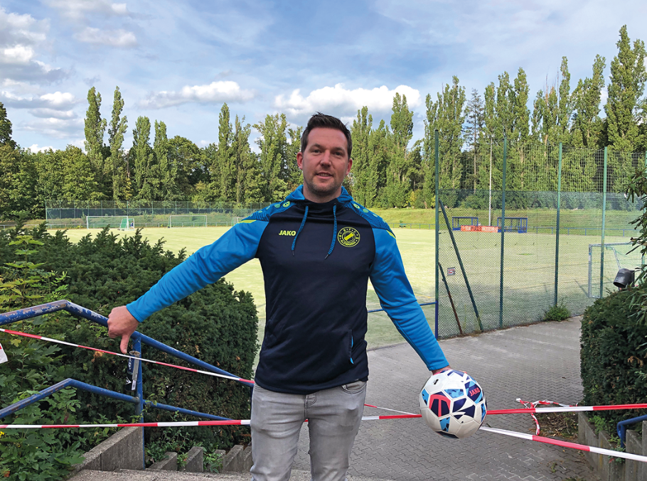Ein Mann im Trainingsanzug vor einem gesperrten Fußballplatz