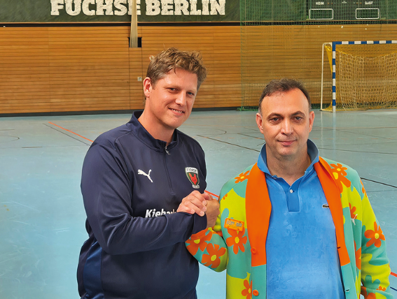 Zwei Männer geben sich die Hand in einer Sporthalle