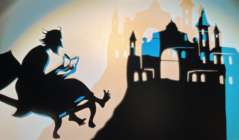 Eine Szene aus einem Schattentheater, im Vordergrund eine lesende Person, im Hintergrund ein Schloss auf einem Berg.