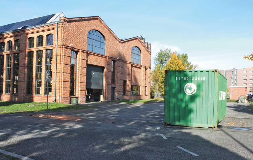 Backsteingebäude mit Hof und grünem Container
