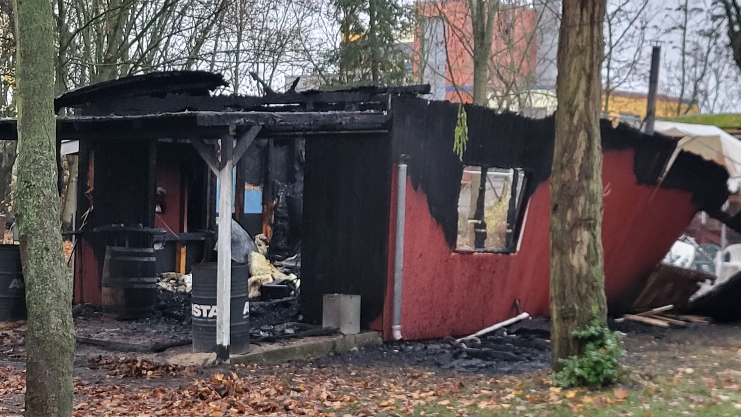 Ein von einem Brand verwüstetes Gebäude, im Hintergrund kahle Bäume.