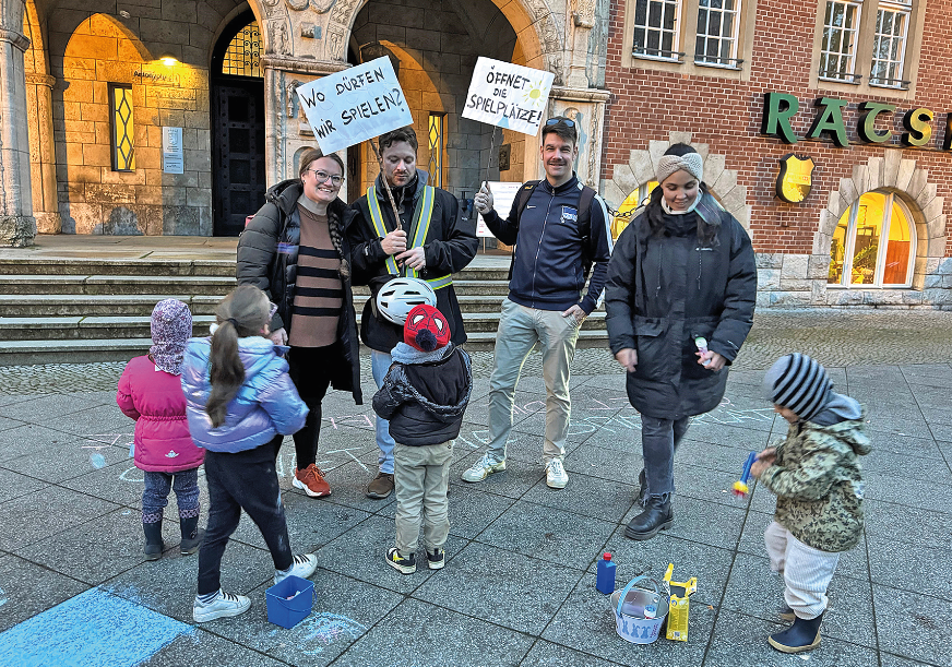 Eltern mit Kindern und Schildern vor dem Rathaus