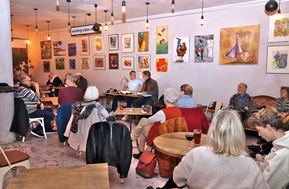 Ein Raum mit Zuhörern und zwei Vorlesenden