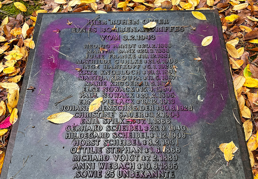 Grabstein, beschmiert mit lila Farbe