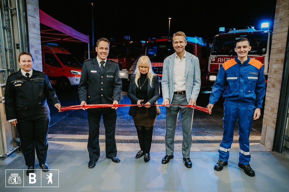 Fünf Menschen vor einem roten Band, das gerade von einer Frau durchgeschnitten wird.