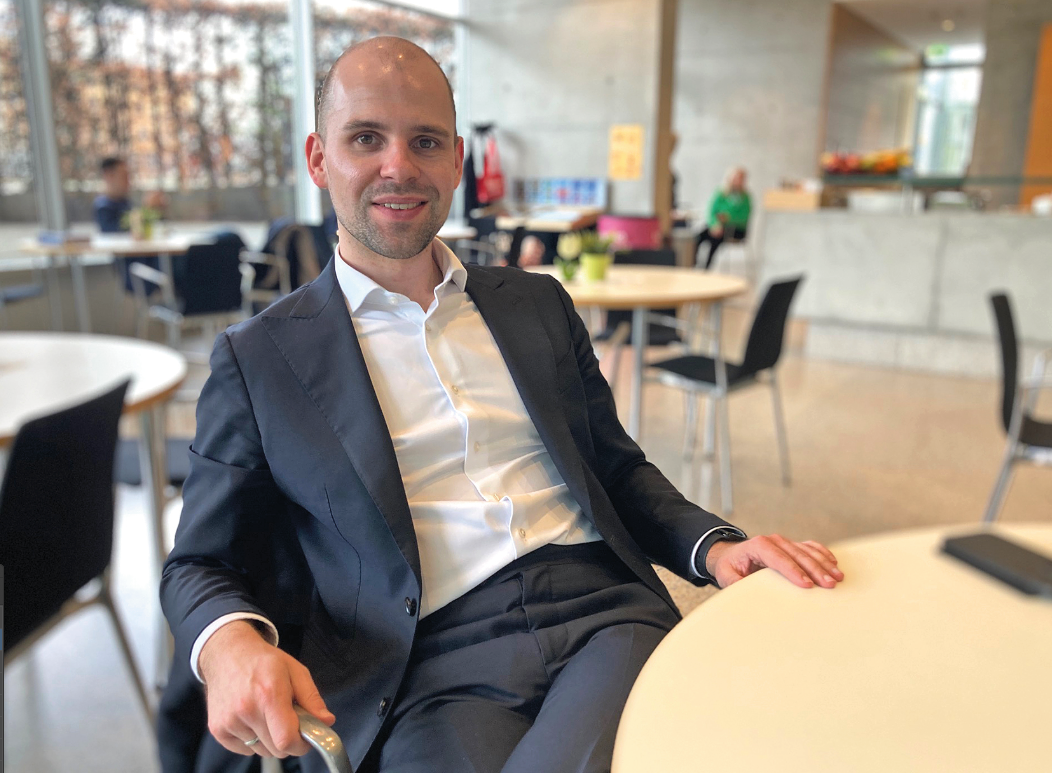 Ein Mann sitzt an einem Tisch und schaut in die Kamera