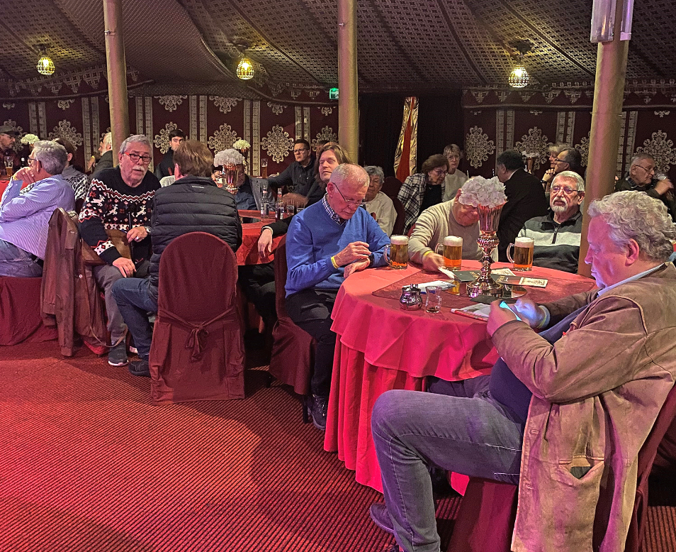 Menchen an Tischen hären in einem Zelt zu