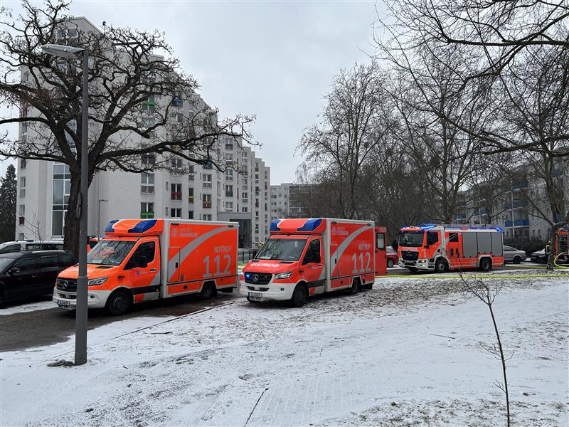 Einsatzwagen von Feuerwehr und Rettungsdienst vor einem Gebäudekomplex in verschneiter Straße