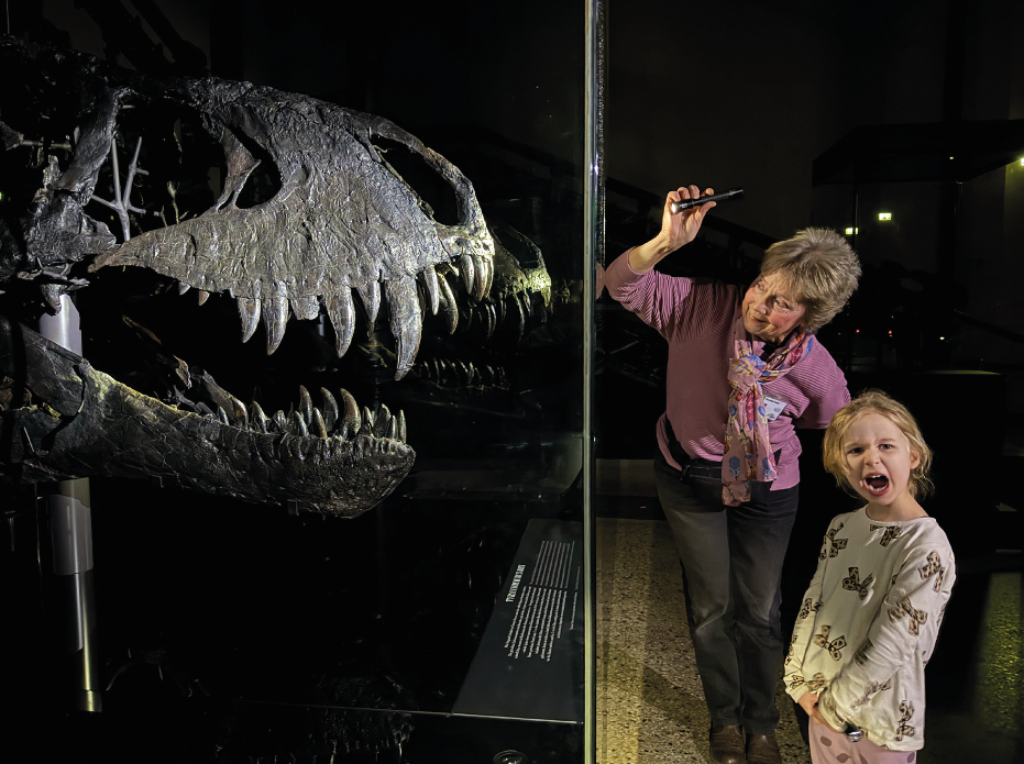 Eine Frau und ein Kind mit Taschenlampen vor einem Dinosaurier-Skelett