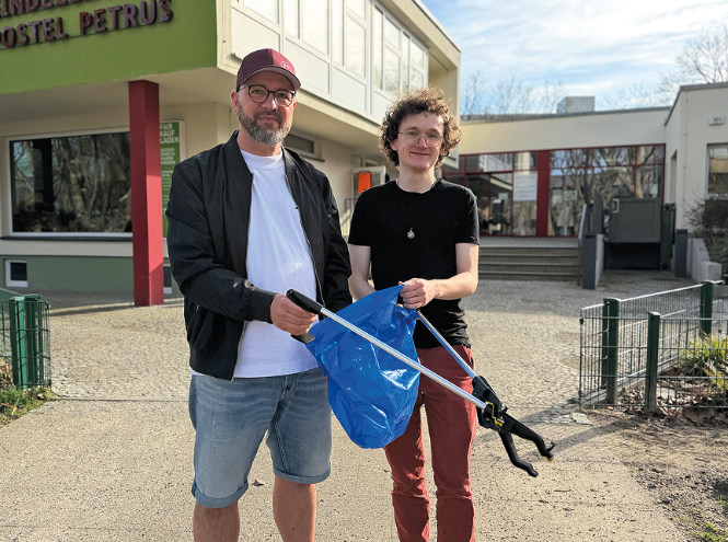 Zwei Männer stehen mit Müsstüte und -greifer bereit