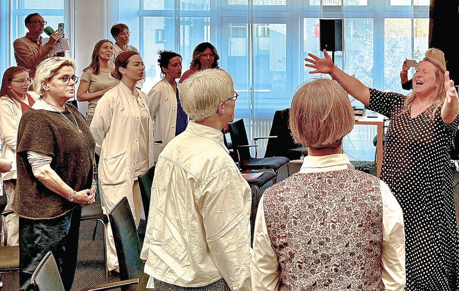 Eine Frau dirigiert Menschen mit Arztkittel und Patienten