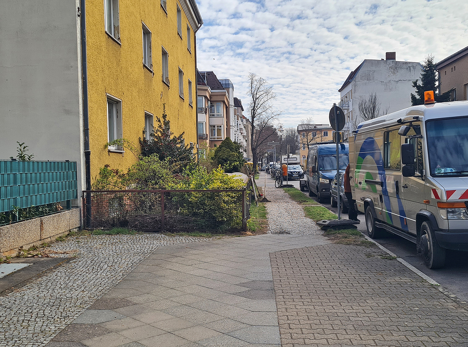 Ansicht einer Straße mit Gehweg, Grünfläche und Steinplatten
