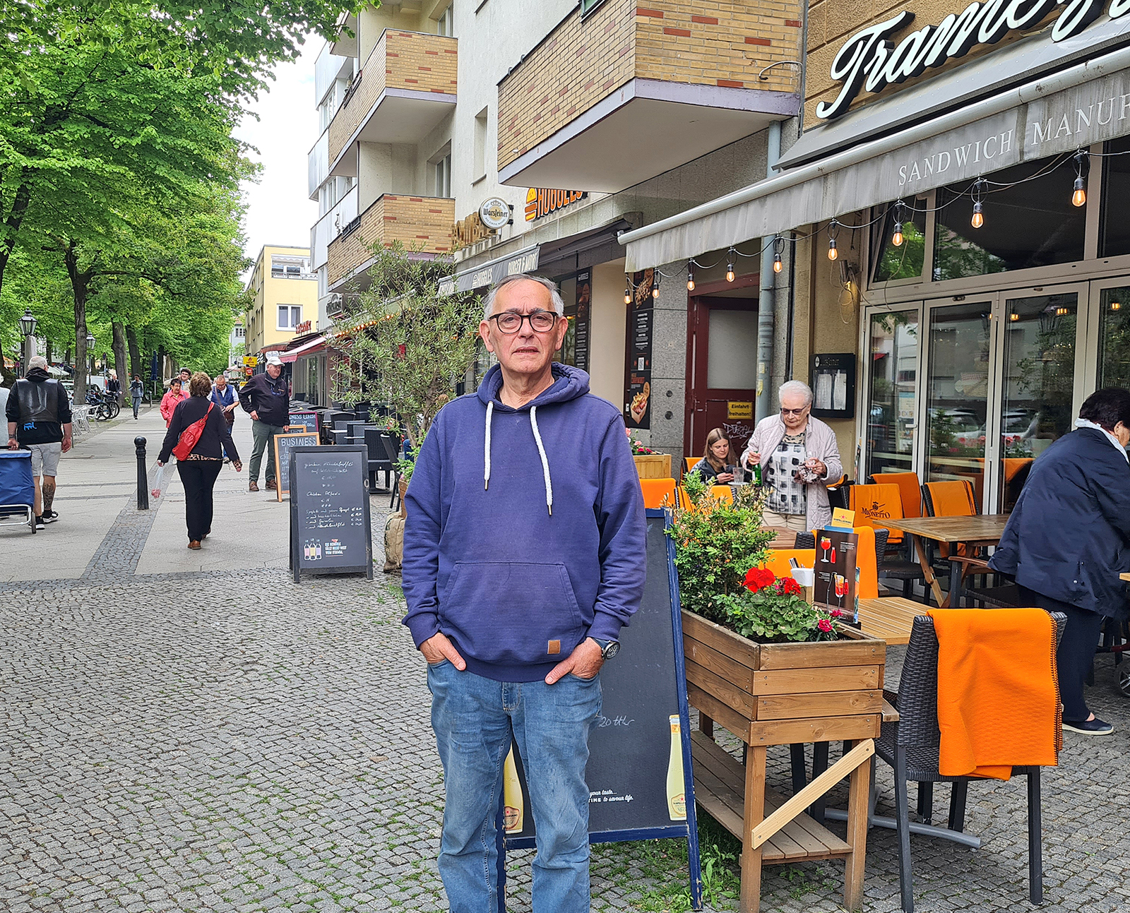 Ein Mann steht in einer Fußgängerzone vor einem Geschäft