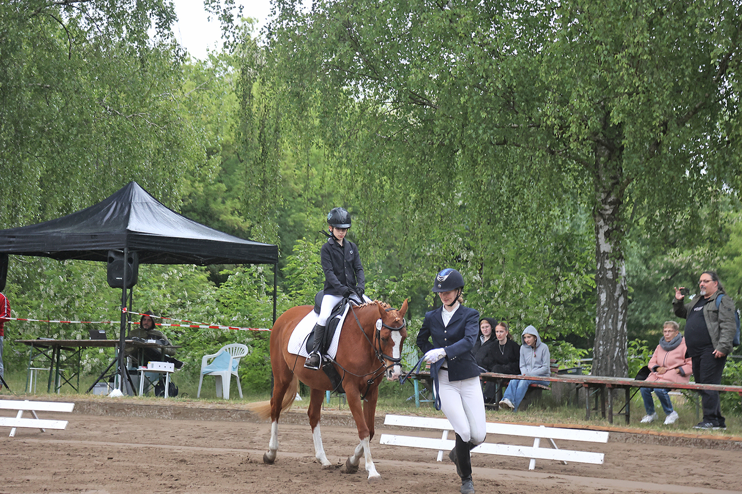 Ein Reiter mit Führungsperson auf einem Reitplatz