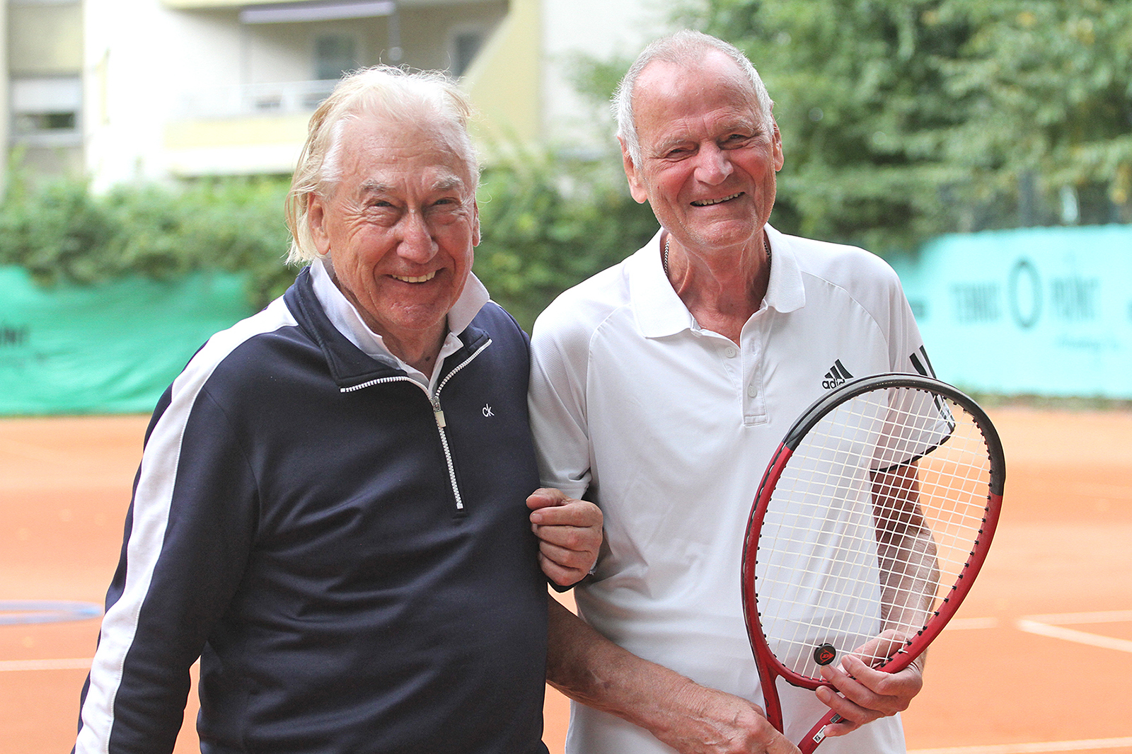 Zwei Tennisspieler vor einem Tennisplatz