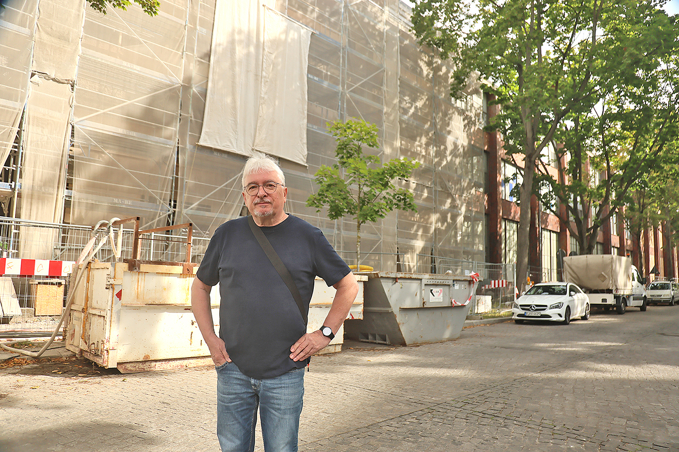 Ein Mann steht auf einer Straße vor einer Baustelle