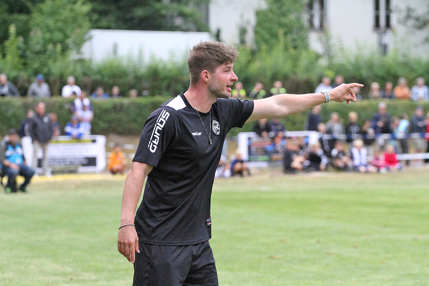 Ein Mann in Sportkleidung gestikuliert am Spielfeldrand